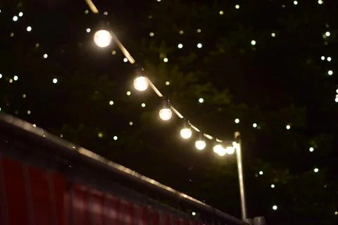 Close up of a string of lights with a christmas tree in the background Stock Photos