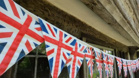 CLOSE UP: String of Union Jack flags strewn under wooden beams of an old house Stock Footage 259233840