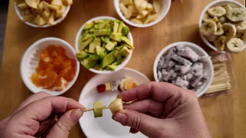 Close-up of stringing pieces of fresh fruit on a wooden skewer to make a light 動画素材 319300397