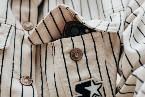 A close-up of a striped jacket with a phone in its pocket, showcasing texture Stock Photos