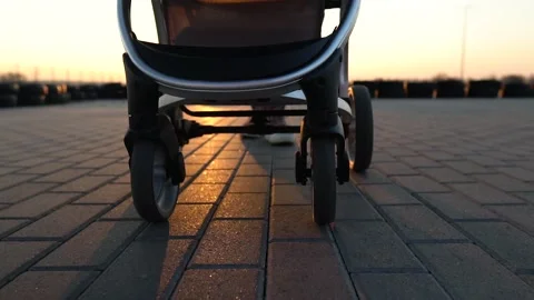 Close up of stroller wheels while mom is walking. Sunset, sunbeams and shadows. Stock Footage 130212113