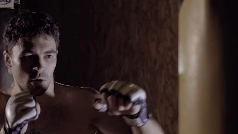 Close-up of strong fair-skinned concentrated man working out using punch sack. Stock-Footage 76916390