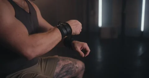 Close-up of a strong man adjusting wrist wraps in a moody gym setting Stock Footage 307495514