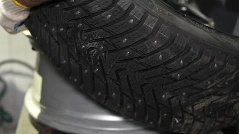 Close-up of studded winter tire tread pattern during installation Stock Footage 347902425