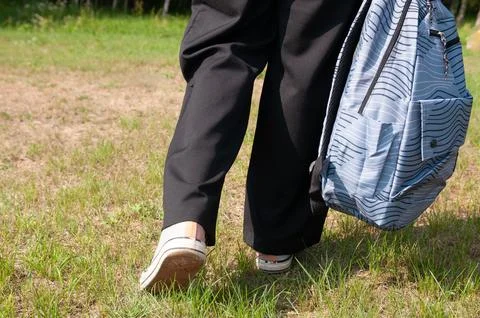 Close-up student going on grass with her backpack 写真素材