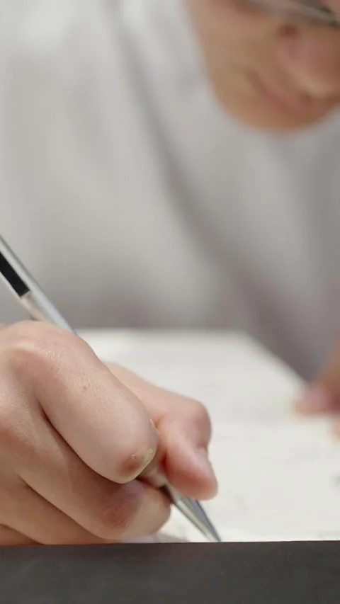 Close up of student hand writing notes in notebook during homework study session Stock Footage 336802104