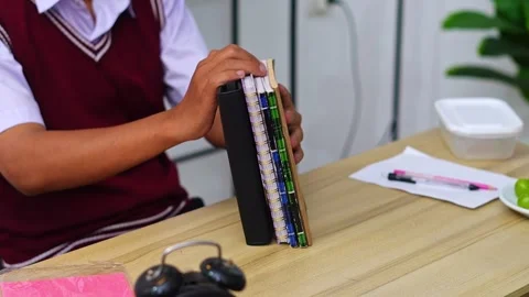 Close up of Student in school uniform organizing stack of notebooks and Stock Footage 335124086
