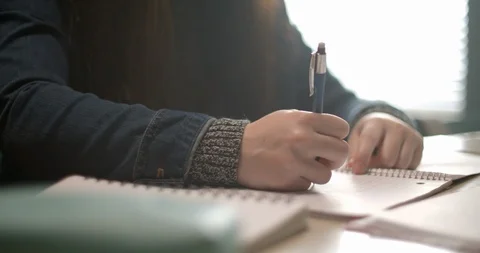 Close up of student taking notes in her notebook while taking online course 스톡 동영상 118142066