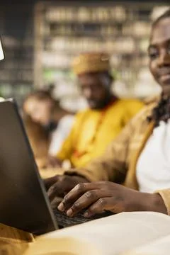 Close-up of student taking notes on laptop beside open book in library space Stock Photos