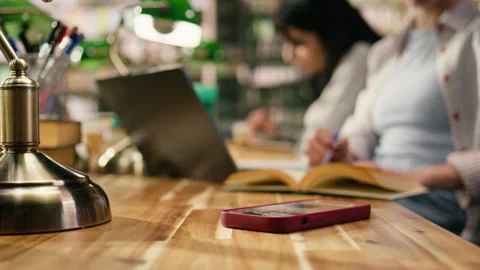 Close up of student using laptop at desk and receives phone message Stock Footage 336358691