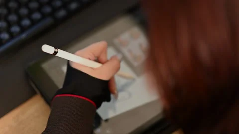 Close up of a student using a white stylus to draw a simple character sketch on Stock Footage 335250300