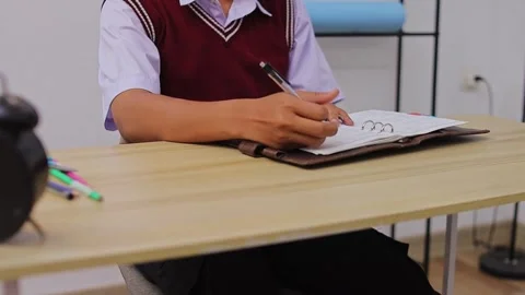 Close-up of student writing in leather journal with black pen at organized desk Stock Footage 335017812