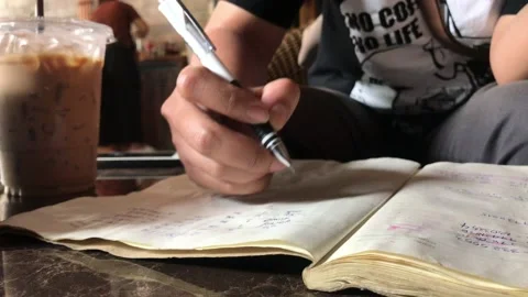 Close up a student writing on a notebook in coffee shop. Stock Footage 117474475