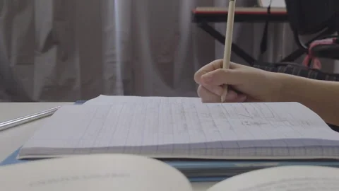 Close-up of a student writing in a notebook during a home study session Stock Footage 332525970
