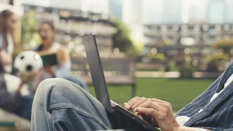 Close up of student writing notes on laptop while sitting on beanbag Stock Photos