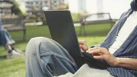 Close up of student writing notes on laptop while sitting on beanbag Stock Photos
