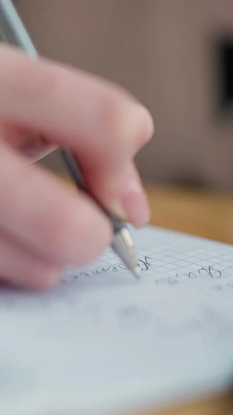 Close-up of student writing notes in notebook with pen on wooden table Видео 318212733