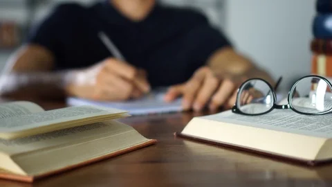 Close-up student writtes in the exercise book. Various books on a desk, Studying Stock Footage 93238152