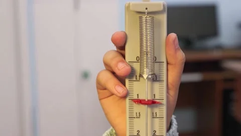 Close-up of a student's hand retracting a spring measuring instrument. Stock Footage 207933725