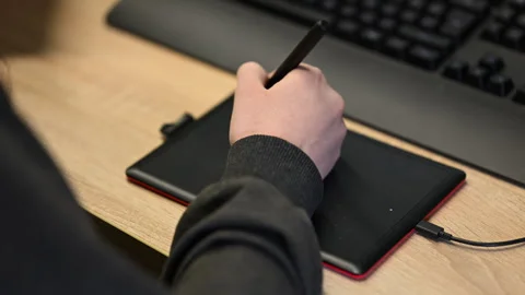 Close up of a student's hand using a black stylus on a compact pen tablet Vídeos de archivo 335253046