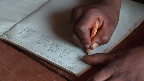 Close-up of student's hand writing math calculations in notebook using a pencil Stock Footage 325710405