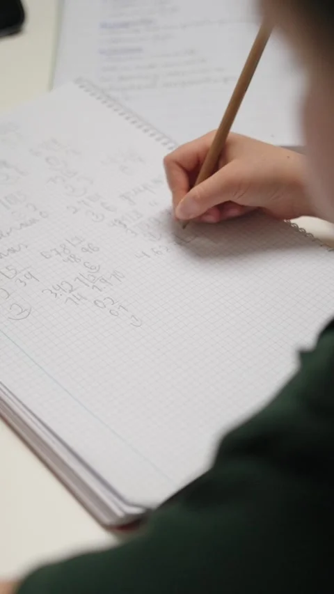 Close-up of a student's hand writing math homework in a notebook. Stock Footage 336618472