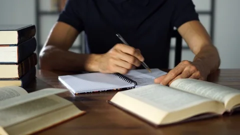 Close-up student's hand writting in a notebook on the table. Studying Stock Footage 93241241