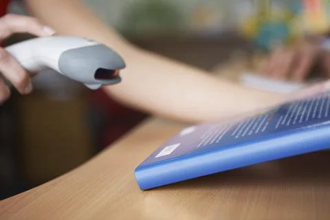 Close-up of student's hands scanning book bar code in library Stock Photos