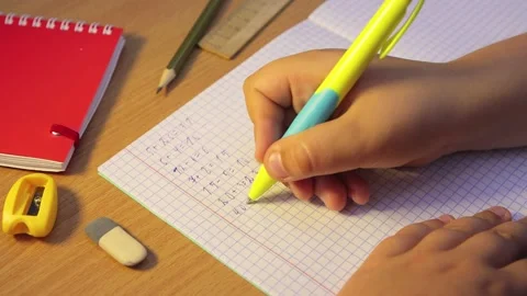Close-up of a student's hands writing numbers in the cells of a notebook. Stock Footage 204982759