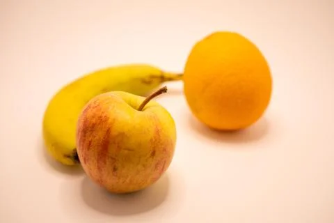A close-up studio shot featuring a red apple, yellow banana, and orange arran Stock Photos