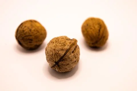 A close-up studio shot featuring three whole walnuts arranged on a plain whit Stock-Fotos