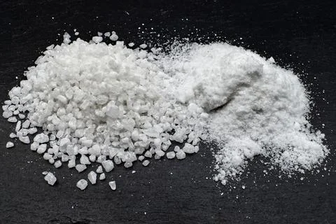A close-up studio shot showing two different textures of white salt granule. Foto stock