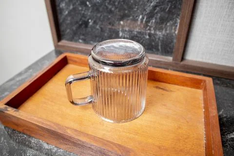 A close-up studio shot of a single inverted ribbed glass mug resting on a w.. Stock-Fotos