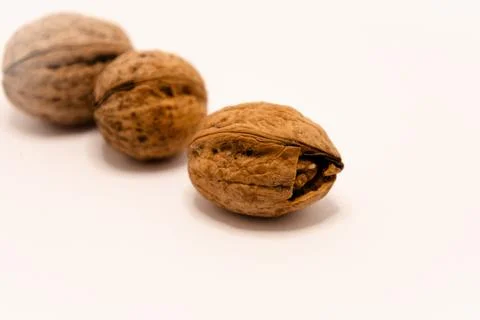 A close-up studio shot of three whole walnuts arranged in a diagonal line aga Fotos de archivo