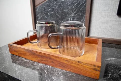 A close-up studio shot of two inverted ribbed glass mugs with looped handle.. Фото