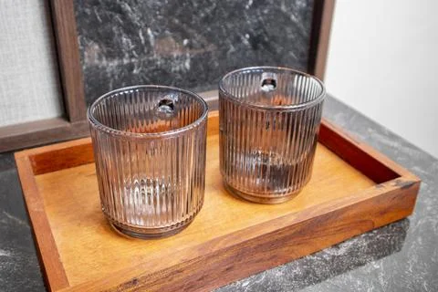 A close-up studio shot of two upright ribbed glass mugs resting on a wooden.. Stock Photos