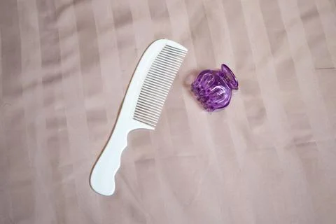 A close-up studio shot of a white plastic hair comb and a purple hair claw .. 写真素材