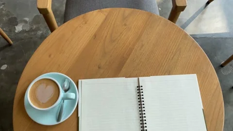 Close up study and work at the cafe. a cup coffee with an open book on the woode Stock Footage 218765712