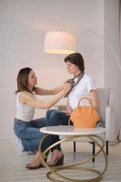 Close-up of a stylist adjusting a patterned scarf on a client, demonstrating the Stock Photos