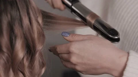 Close-up of the stylist performs a curl of light hair. Waves in the hair salon. Stock Footage 148525412