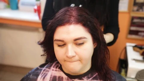 Close up of stylist using flat iron on  hair of female client in salon Stock Footage 101032813