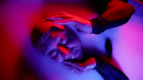 Close-up of a suffering and screaming man lying in a white liquid and biting his Vídeos de archivo 221567649