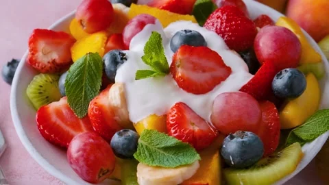 Close up of summer colorful fruit salad with Greek yogurt in a bowl on pink Stock Footage 315860507