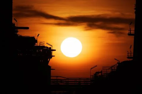Close up of the sun during sunset in the evening twilight between 2 oil refin Stock Photos