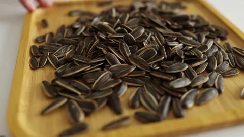 Close-up of sunflower seeds on a rotating square wooden plate. Stock Footage 344646578