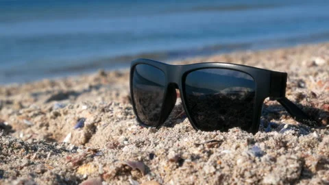 Close-up of sunglasses on the sand by the surf 스톡 동영상 151172177