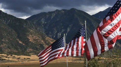 Close up-Sunlit American flags against dark sky and mountain Stock Footage 68334423