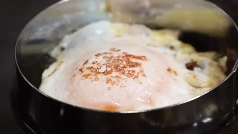 Close-up of a Sunny Side Up Egg Frying in a Metal Ring with Chili Oil Stockbeeldmateriaal 331633222