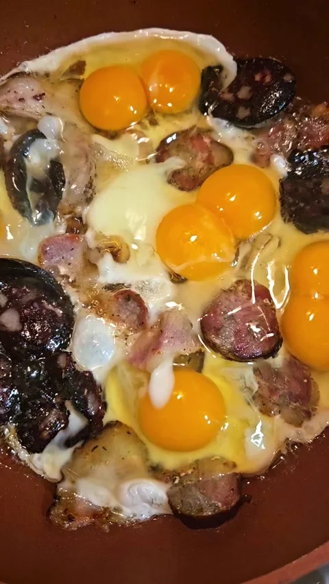 Close-up of sunny-side up eggs frying with pork sausage and blood sausage Stock Footage 346224581