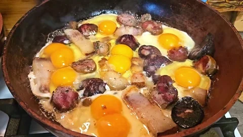 Close-up of sunny-side up eggs frying with pork sausage and blood sausage Stock Footage 346224583